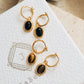 Close-up of gold vermeil dangle earrings with an oval black onyx gemstone or tiger's eye gemstone on a jewellery box, minimalist and elegant style