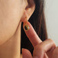 A tiger's eye oval gemstone earring worn on a woman's ear showcasing its details and exquisite craftmanship