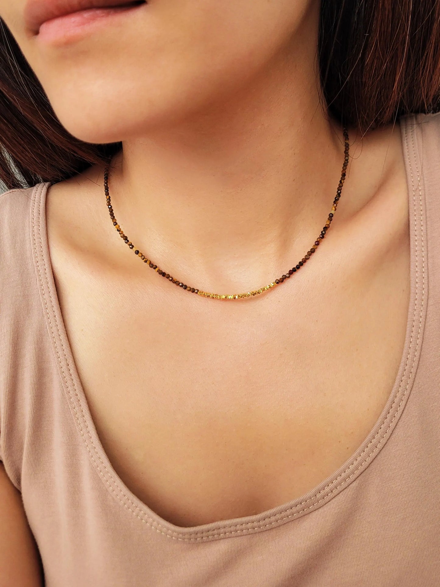Woman wearing a delicate tiger's eye choker necklace with gold vermeil beads, boho chic style.