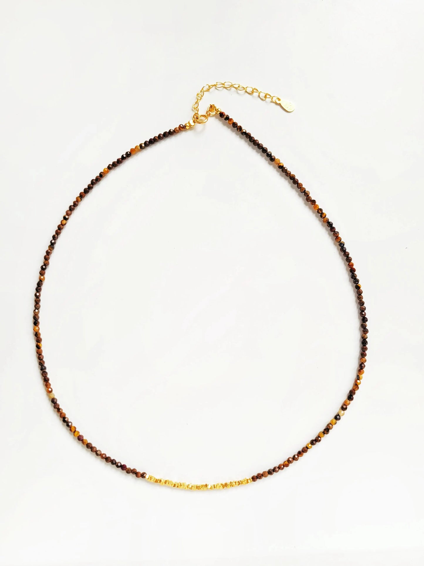 Necklace with natural tiger's eye gemstone and gold accents on a neutral background