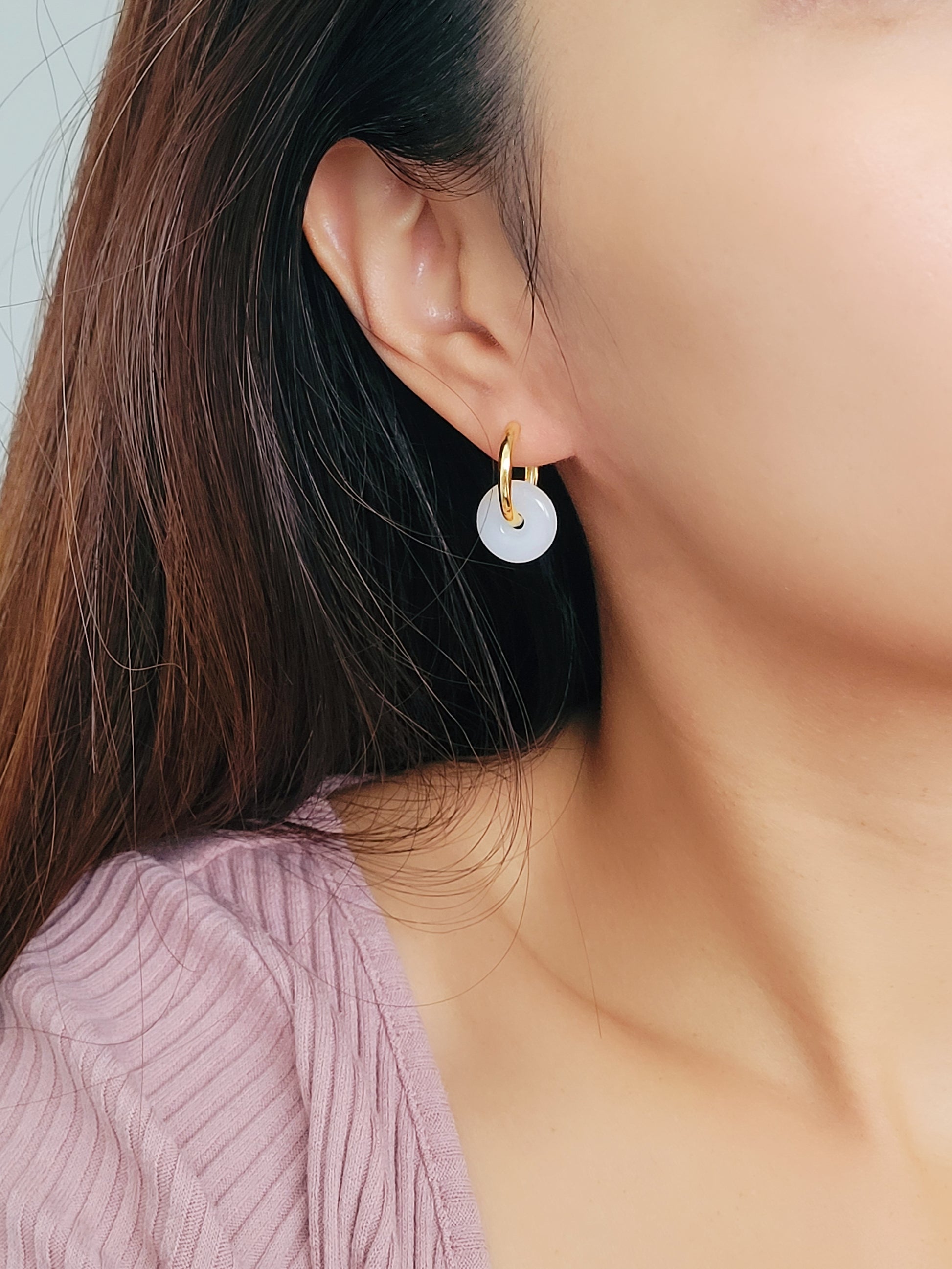 A woman showcasing her stunning and unusual earrings crafted in yellow gold vermeil with jade drop and enamel disc.