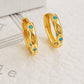 A pair of textured 18K gold-plated over 925 sterling silver huggie earrings featuring engraved star patterns and inlaid vibrant turquoise stones, shown close up.