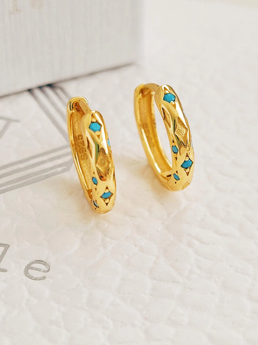 A pair of textured 18K gold-plated over 925 sterling silver huggie earrings featuring engraved star patterns and inlaid vibrant turquoise stones, shown close up.