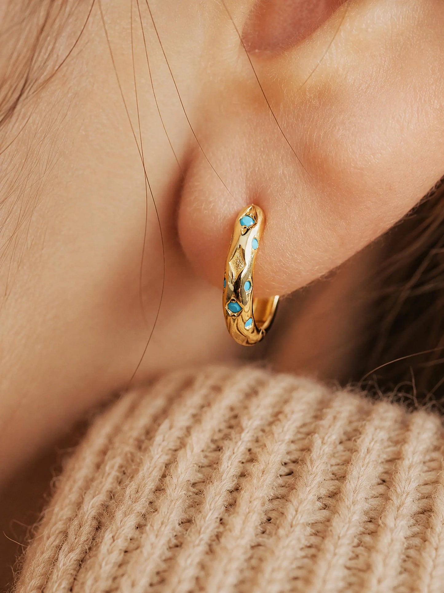 Close up of a woman wearing Turquoise star huggie hoop earring crafted in gold plated sterling silver, featuring a cosmic star inspired design. Minimalist earring design, perfect birthday gift for her.