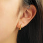 Close up of a woman wearing Turquoise star huggie hoop earring crafted in gold plated sterling silver, featuring a cosmic star inspired design. Minimalist earring design, perfect birthday gift for her.
