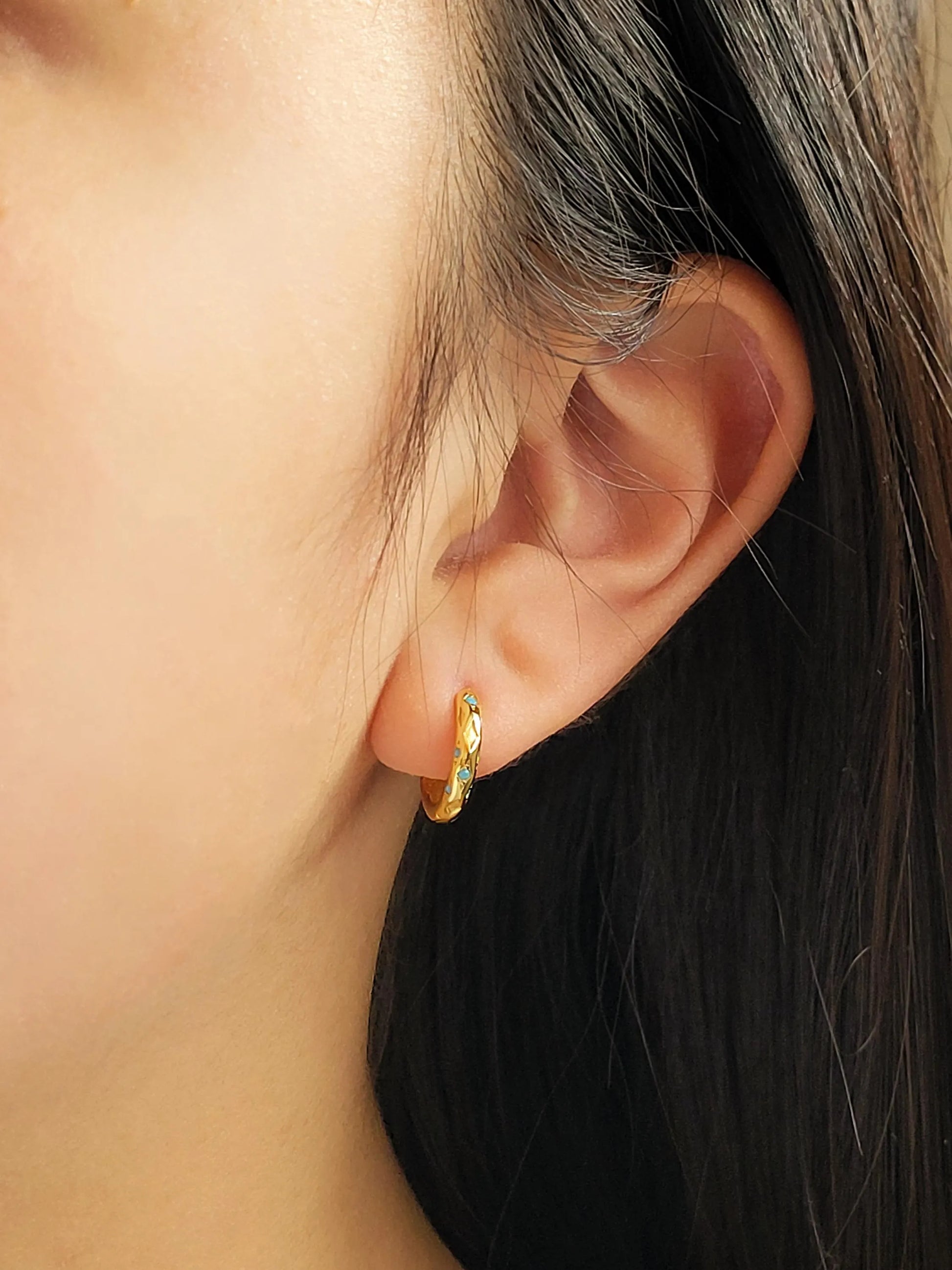 Close up of a woman wearing Turquoise star huggie hoop earring crafted in gold plated sterling silver, featuring a cosmic star inspired design. Minimalist earring design, perfect birthday gift for her.