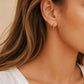 Close up of a woman wearing Turquoise star huggie hoop earring crafted in gold plated sterling silver, featuring a cosmic star inspired design. Minimalist earring design, perfect birthday gift for her.