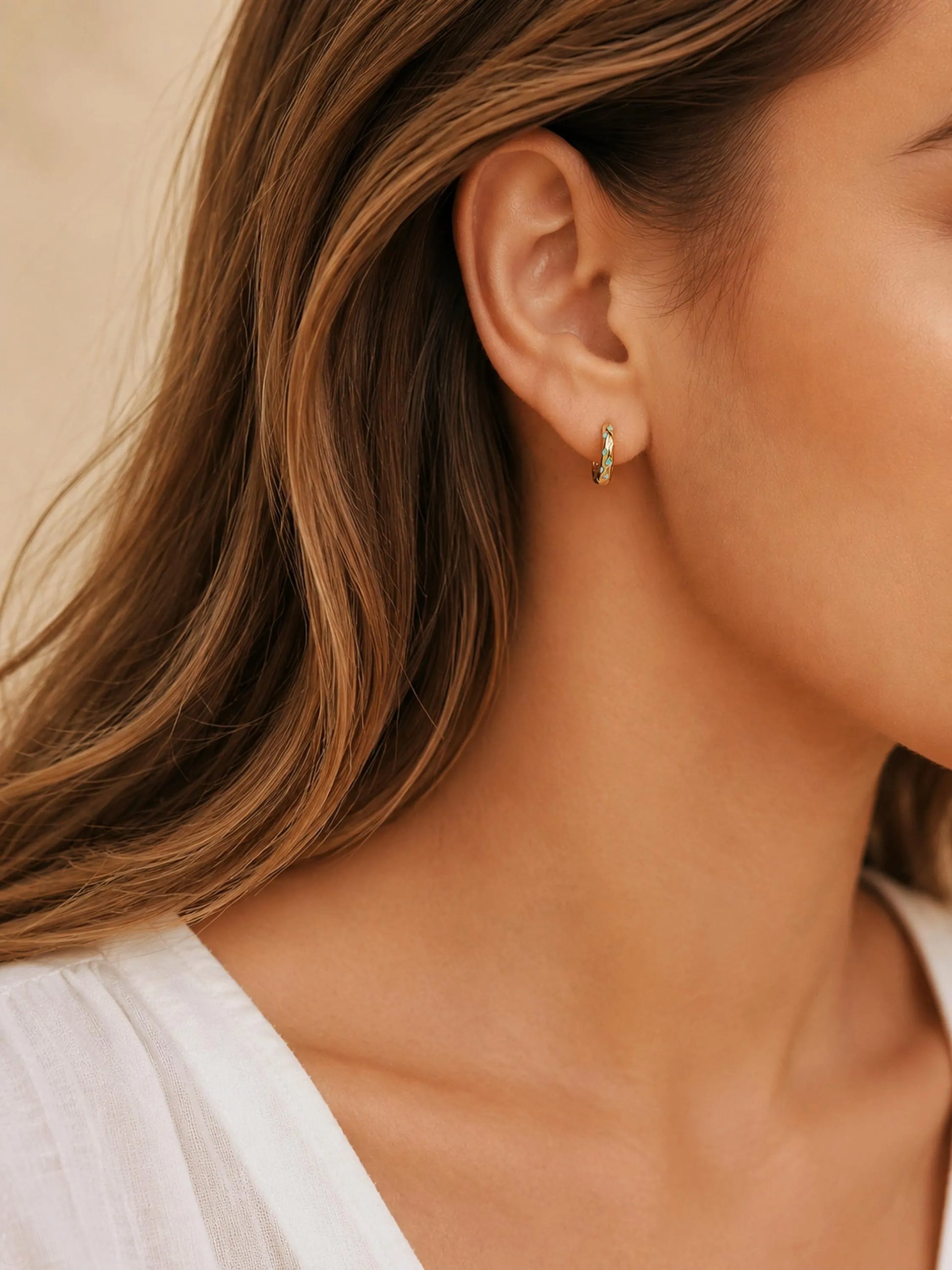 Close up of a woman wearing Turquoise star huggie hoop earring crafted in gold plated sterling silver, featuring a cosmic star inspired design. Minimalist earring design, perfect birthday gift for her.