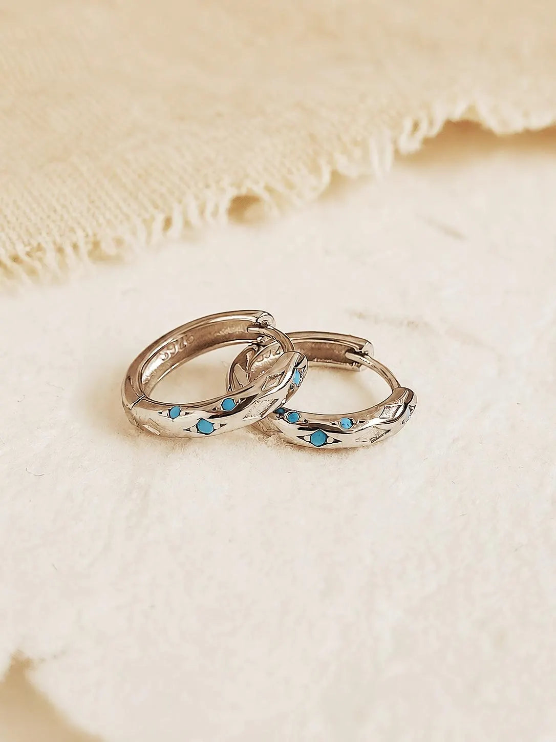 Close up of Turquoise star huggie hoop earring crafted in sterling silver, featuring a cosmic star inspired design. Minimalist earring design, perfect birthday gift for her.