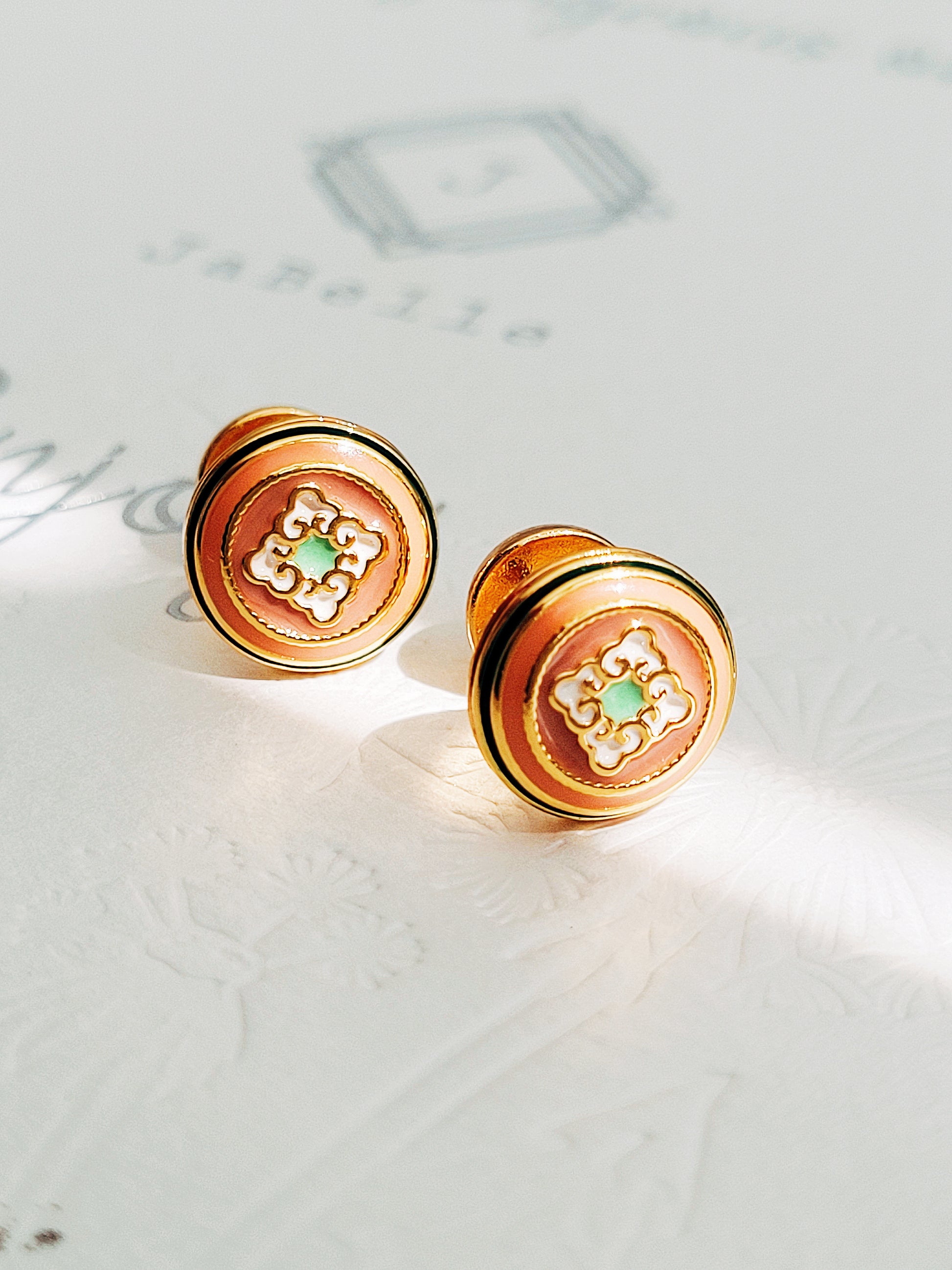 Beautiful gold earrings showcasing a unique tile pattern for a trendy accessory. Hand painted enamel with beige, green and white colour highlighting the detailed vintage tile pattern.