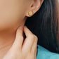 A woman with long hair adorned with a gold tile pattern earring ,exuding elegance and charm.