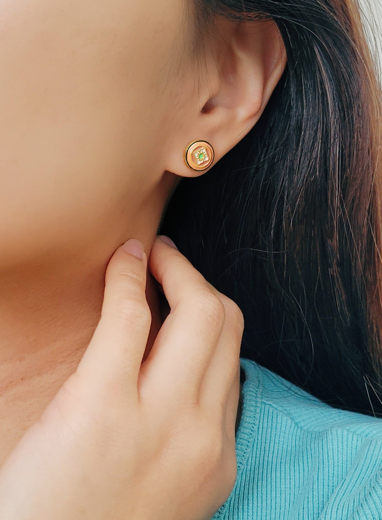 A woman with long hair adorned with a gold tile pattern earring ,exuding elegance and charm.