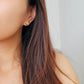 A woman with long hair adorned with a gold tile pattern earring ,exuding elegance and charm.