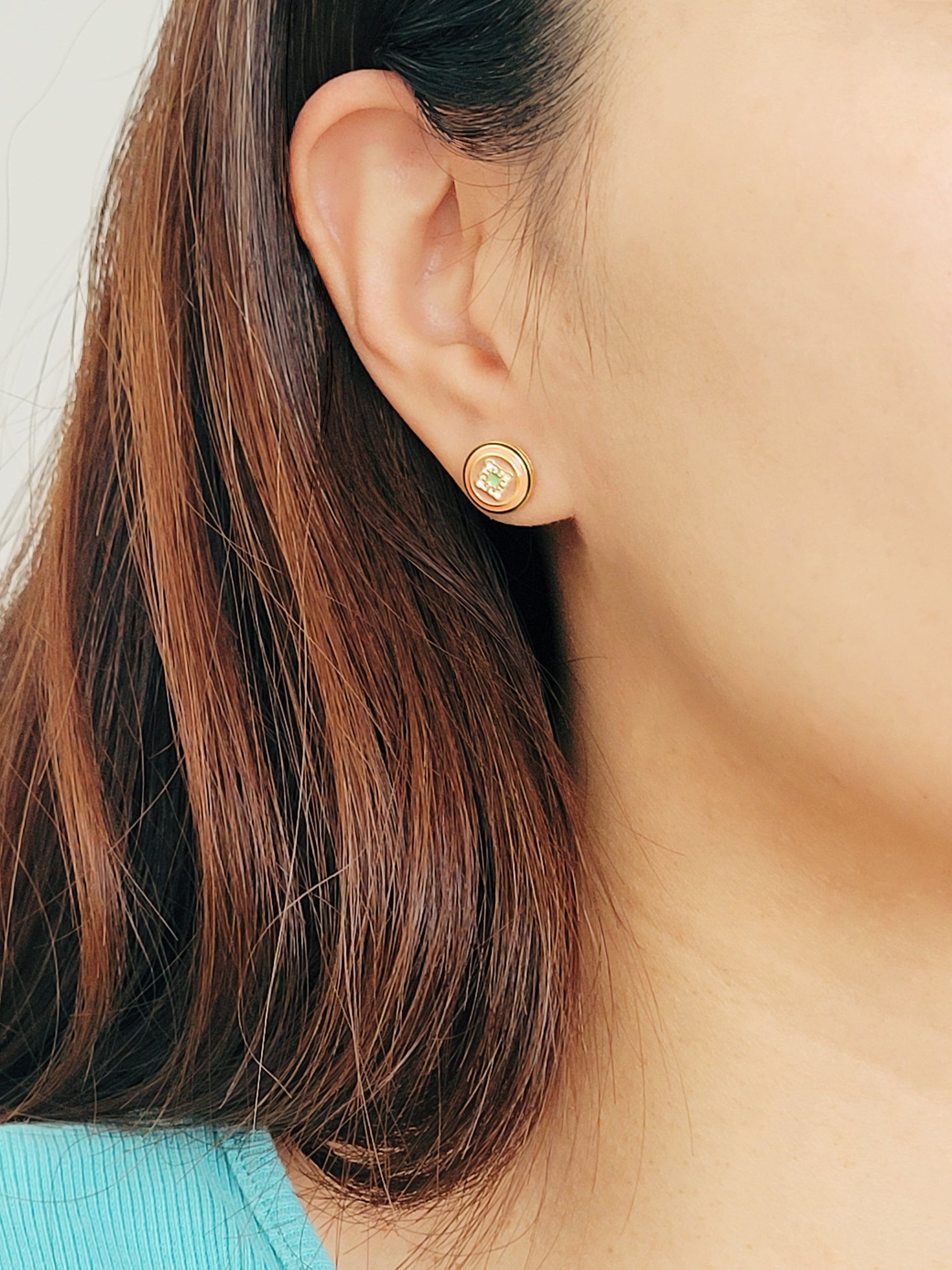 A woman with long hair adorned with a gold tile pattern earring ,exuding elegance and charm.