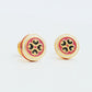Closeup of retro-style stud earrings featuring a pink and dark green geometric tile pattern with gold accents. These vintage-inspired enamel earrings offer a classic, timeless design adding a touch of elegance to any outfit.