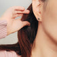Close-up of a woman's ear wearing a pair of Retro Gothic tile pattern enamel stud earrings in pink, dark green, and gold. The intricate design features a vintage-style pattern with a bold color combination, creating a striking and elegant look.