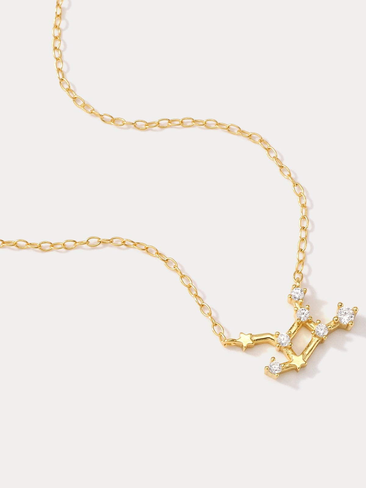 A dainty gold necklace with a pendant featuring a stylized Virgo zodiac constellation sign with sparkling zircons, crafted in gold plated sterling silver.