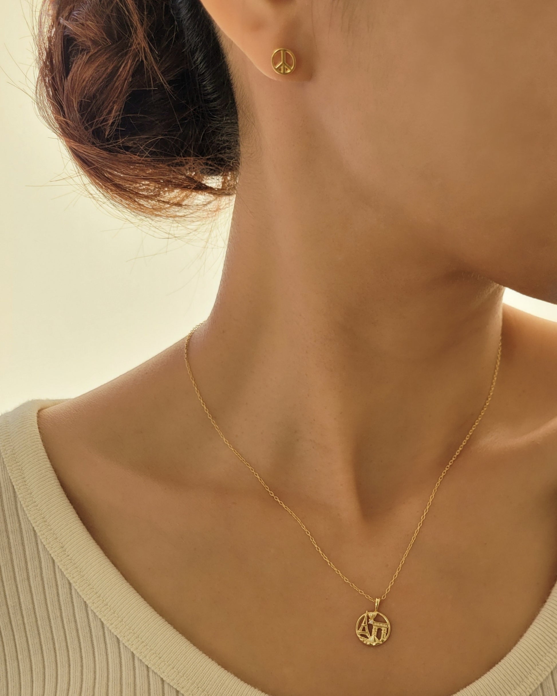 Woman wearing gold pendant necklace with Paris themed details